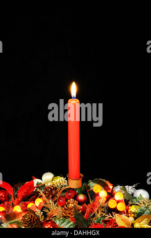 Candela rossa, Natale fiori e a bacca rossa luci contro uno sfondo nero. Foto Stock