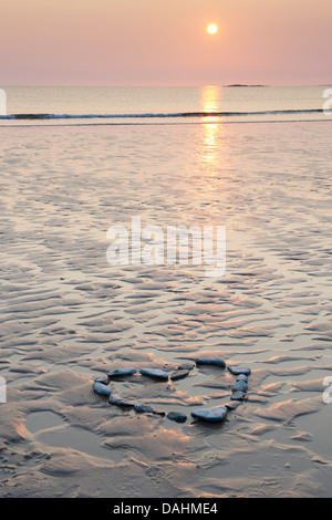 Forma di cuore i ciottoli su una spiaggia a sunrise. Regno Unito Foto Stock