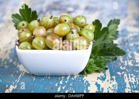 Uva spina nella ciotola con foglie su un tavolo di legno sfondo Foto Stock