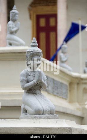 Inginocchiarsi di statue nel palazzo reale di Phnom Penh Cambogia con bandiera in background Foto Stock