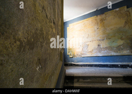 Un danneggiato in stucco di colore giallo sulla parete per interni Foto Stock