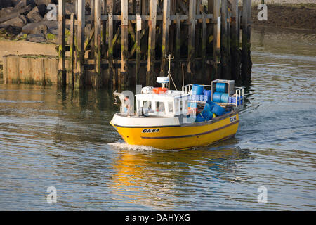 Un giallo barca da pesca capo sout su acque di Cardigan Bay come golden tramonto su Aberystwyth. Foto Stock