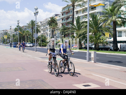 Due giovani uomini in bicicletta lungo la promenade di Nizza, Francia Foto Stock