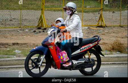 Una madre corre con il suo piccolo uno su una motocicletta per le vie della città di Ho Chi Minh, Vietnam, 30 marzo 2011. Foto: Arno Burgi Foto Stock