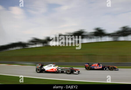 British pilota di Formula Uno Lewis Hamilton (anteriore) della McLaren Mercedes e Swiss driver di Formula Uno di Sebastien Buemi Toro Rosso sterzare le vetture durante la sessione di qualifiche sul circuito di Sepang, al di fuori di Kuala Lumpur, Malesia, 09 aprile 2011. Il Gran Premio di Formula Uno di Malesia avrà luogo il 10 aprile 2011. Foto: Jens Buettner dpa Foto Stock