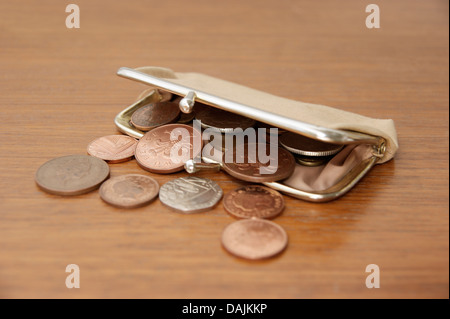 Una borsa riempita di monete (sterlina inglese denaro) riversandosi su un tavolo Foto Stock