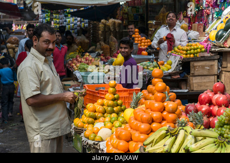 Venditore ambulante disponendo le arance per la vendita a una pressione di stallo di frutta Foto Stock