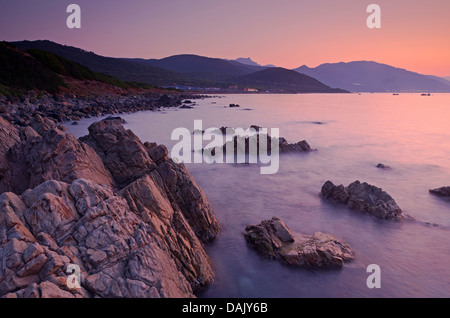 Sunrise dietro le montagne della Corsica vicino a Ajaccio con la rocciosa costa mediterranea in primo piano. Ajaccio è il Foto Stock