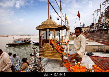 Sacerdote con il piccolo tempio a Ghat, Dashashwamedh Ghat Varanasi, Uttar Pradesh, India Foto Stock