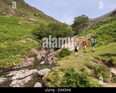 Walkers accanto a una piccola cascata su Afon Cwm Llan fiume nel Parco Nazionale di Snowdonia. Bethania, Gwynedd, il Galles del Nord, Regno Unito, Gran Bretagna Foto Stock