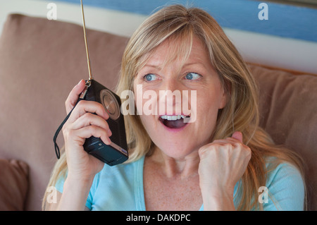 Donna ascoltando la radio a transistor con anticipazione. Foto Stock