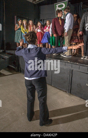 Un insegnante di arte drammatica mostra i suoi studenti come prendere una prua per la finale di uno studente di produzione musicale del 'grasso' . Foto Stock