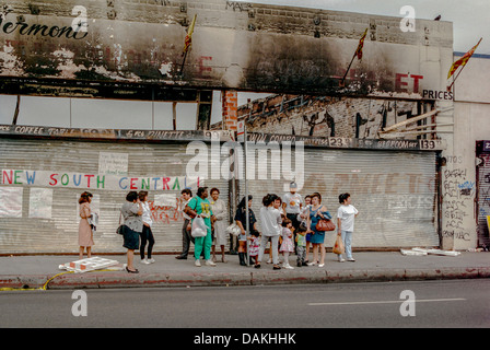 Multietniche locali attendere per un autobus di fronte a fuoco negozi danneggiati in South Central Los Angeles dopo 1992 Rodney King gara sommossa. Foto Stock