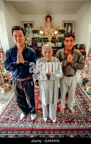 Un buddista vietnamita sacerdote prega con due giovani uomini vietnamita nel suo tempio di fortuna si trova in una casa a Santa Ana CA. Foto Stock