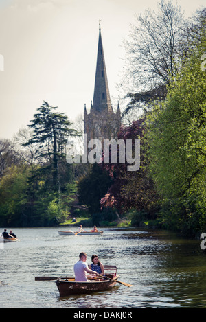 Le coppie in barca sulle rive del fiume Avon in Stratford-Upon-Avon, Regno Unito con la chiesa della Trinità in background Foto Stock