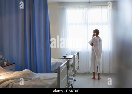 Paziente in vestaglia parlando al cellulare nella stanza di ospedale Foto Stock