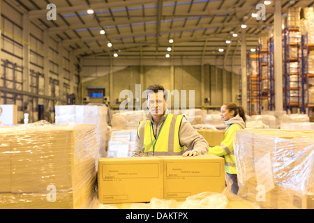 Lavoratore disimballaggio scatole in magazzino Foto Stock