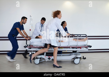 Il personale ospedaliero rushing paziente in sala operatoria Foto Stock