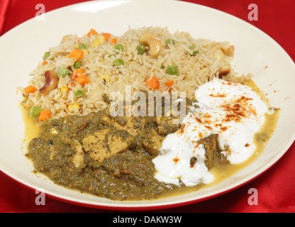 Un pasto di pollo Saag (spinaci) curry servita con yogurt e peperoncino e un vegetale pulau riso Foto Stock