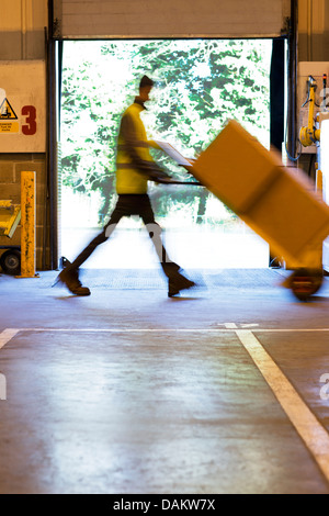 Vista offuscata del lavoratore scatole per il karting in magazzino Foto Stock