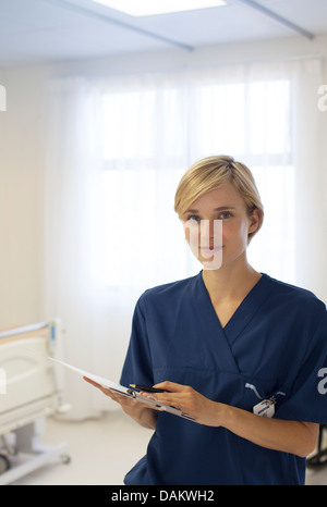 Infermiere negli appunti di lettura in ospedale in corridoio Foto Stock
