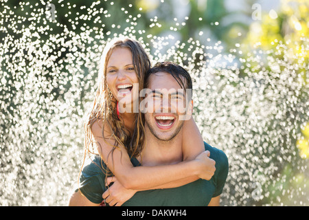 Giovane giocando in impianti sprinkler in cortile Foto Stock