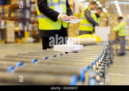 Lavoratori controllo pacchetti sul nastro trasportatore in magazzino Foto Stock