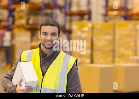 Lavoratore scatola portante in magazzino Foto Stock