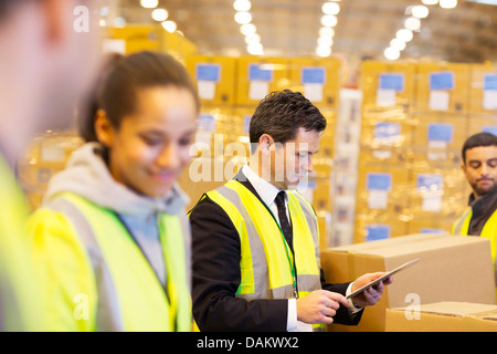 Imprenditore e lavoratori in magazzino Foto Stock