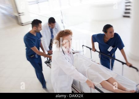 Il personale ospedaliero rushing paziente in sala operatoria Foto Stock