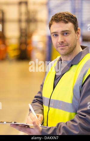 Lavoratore utilizzando gli appunti in magazzino Foto Stock