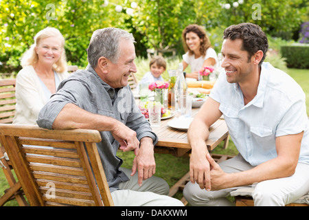 La famiglia seduta a tavola all'aperto Foto Stock