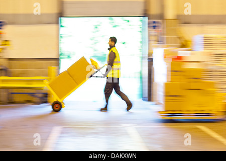 Vista offuscata del lavoratore spinge scatole in magazzino Foto Stock