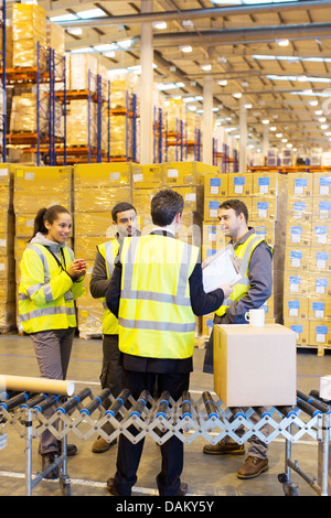 Imprenditore e lavoratori parlando in magazzino Foto Stock