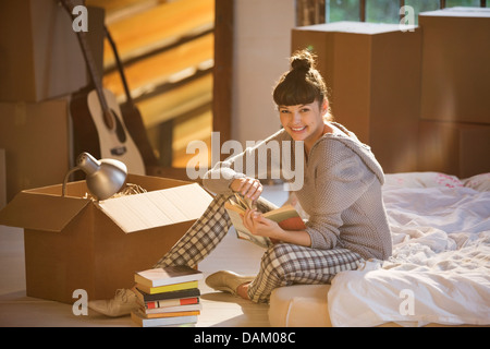 Donna azienda prenota nel letto Foto Stock