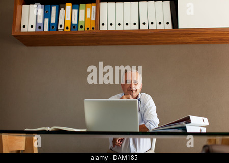 Vecchio uomo seduto alla scrivania Foto Stock