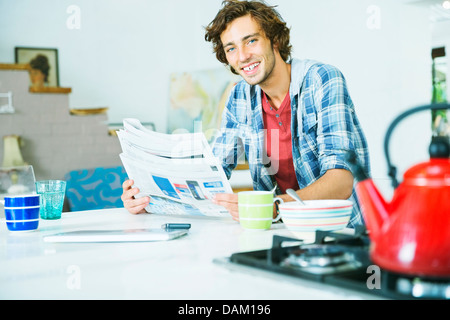 Uomo che legge il giornale in cucina Foto Stock