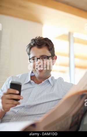 Uomo con cellulare sul divano Foto Stock