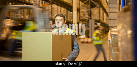 Lavoratore scatola portante in magazzino Foto Stock