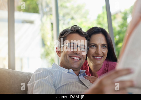 Accoppiare la lettura di giornale insieme sul divano Foto Stock