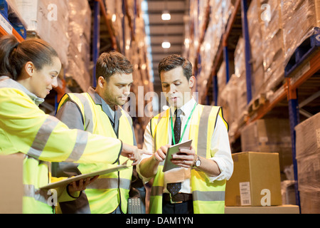 Imprenditore e lavoratori parlando in magazzino Foto Stock