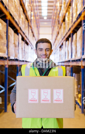 Lavoratore che trasportano 'Fragile' box in magazzino Foto Stock