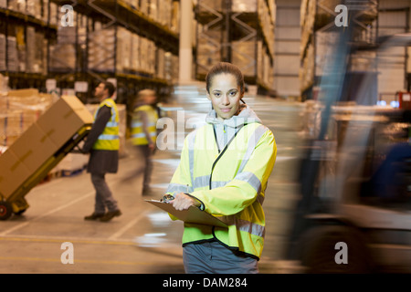 Lavoratore negli appunti di contenimento in magazzino Foto Stock