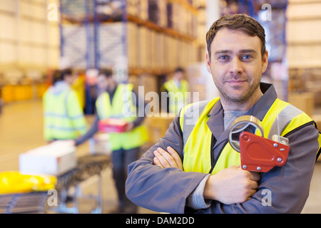 Lavoratore azienda distributore di nastro in magazzino Foto Stock