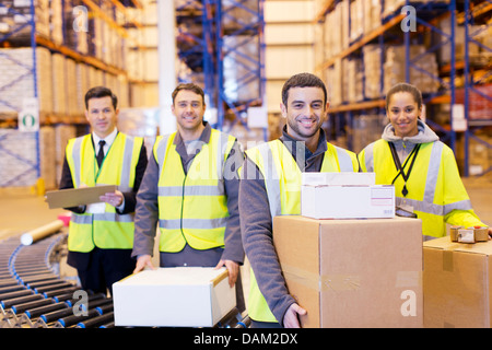 Lavoratori sorridente dal nastro trasportatore in magazzino Foto Stock