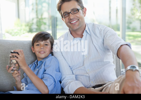 Padre e Figlio con cambio jar sul divano Foto Stock