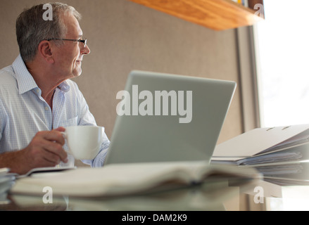 Imprenditore avente tazza di caffè al laptop Foto Stock