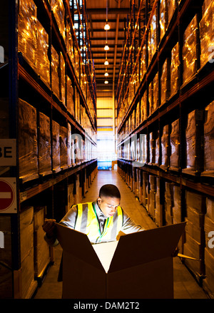 Lavoratore apertura casella incandescente in magazzino Foto Stock