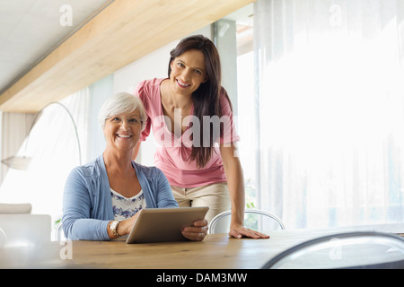 Le donne che usano i computer tablet a tavola Foto Stock