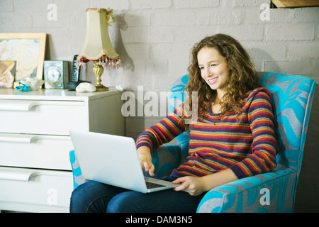 Donna che utilizza computer portatile in poltrona Foto Stock